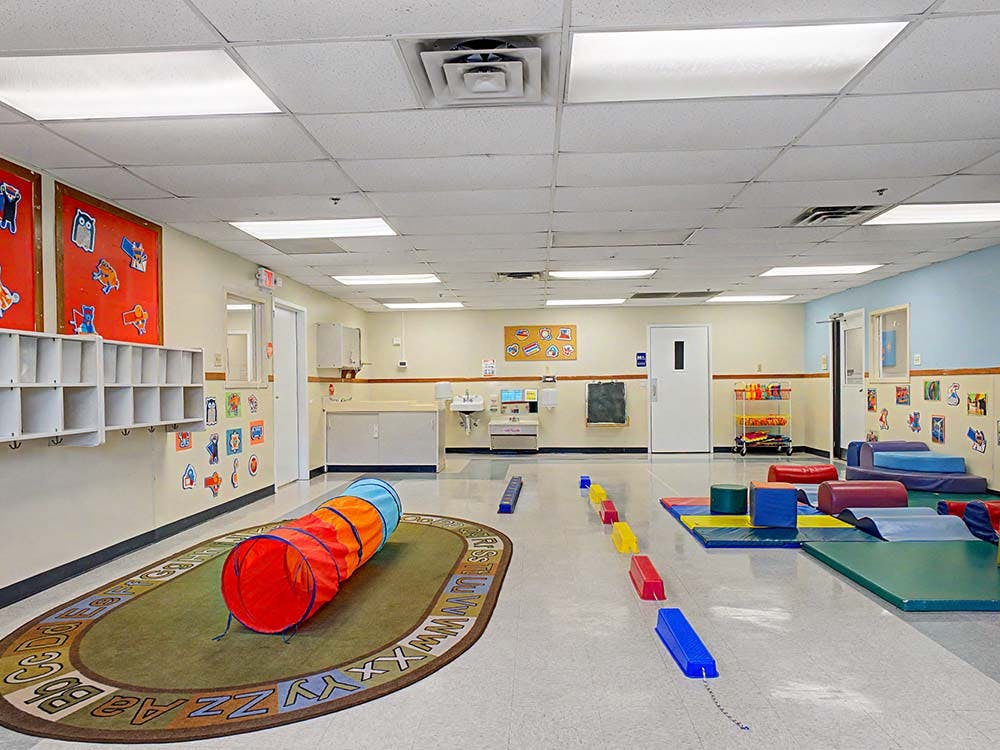 Colorful playroom with soft mats, play tunnel, and ABC rug