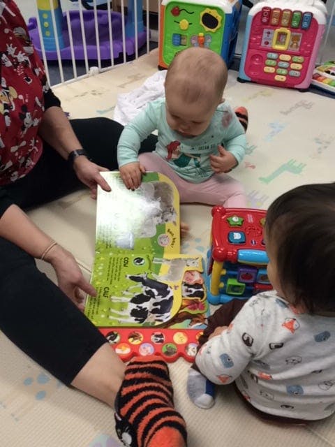 Person and two children on floor looking at a book