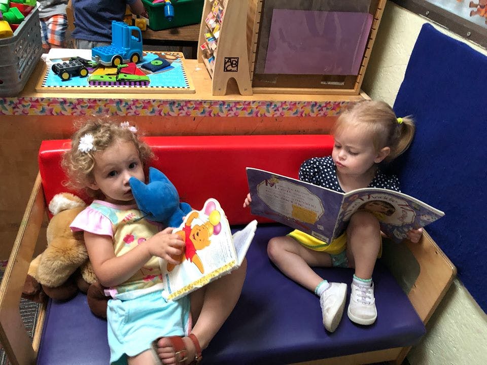 Two children sitting and reading books