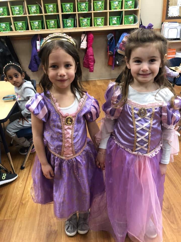 Two children in purple dresses standing in a classroom