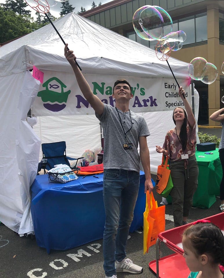 Two people making bubbles with wands at an outdoor event