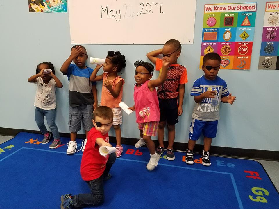 Group of children playing with paper cups in a classroom