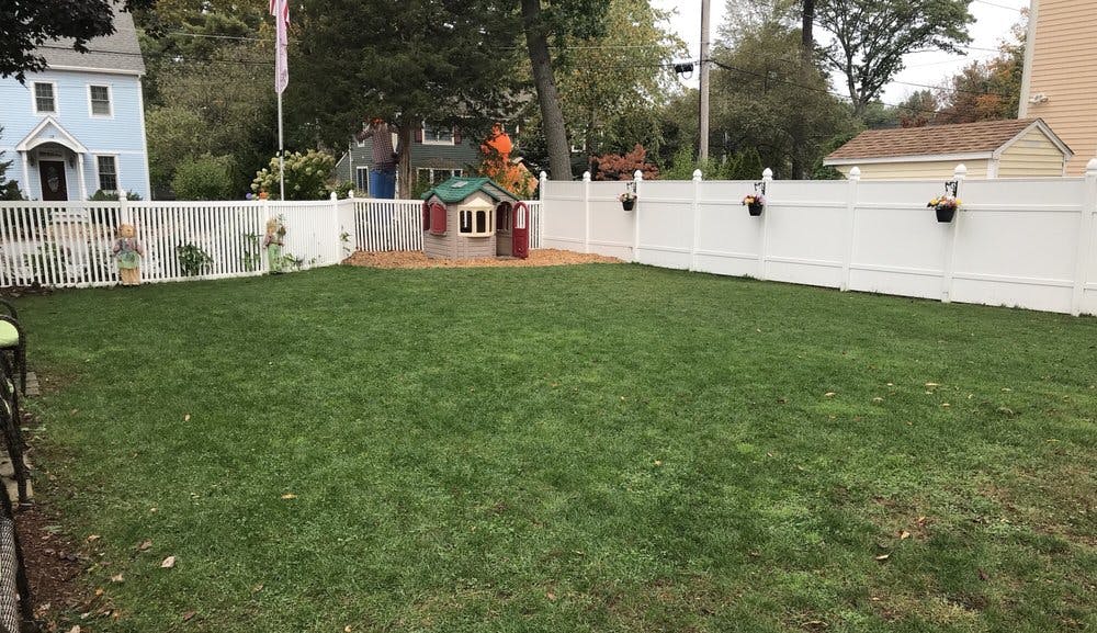 Backyard with green grass and white fence
