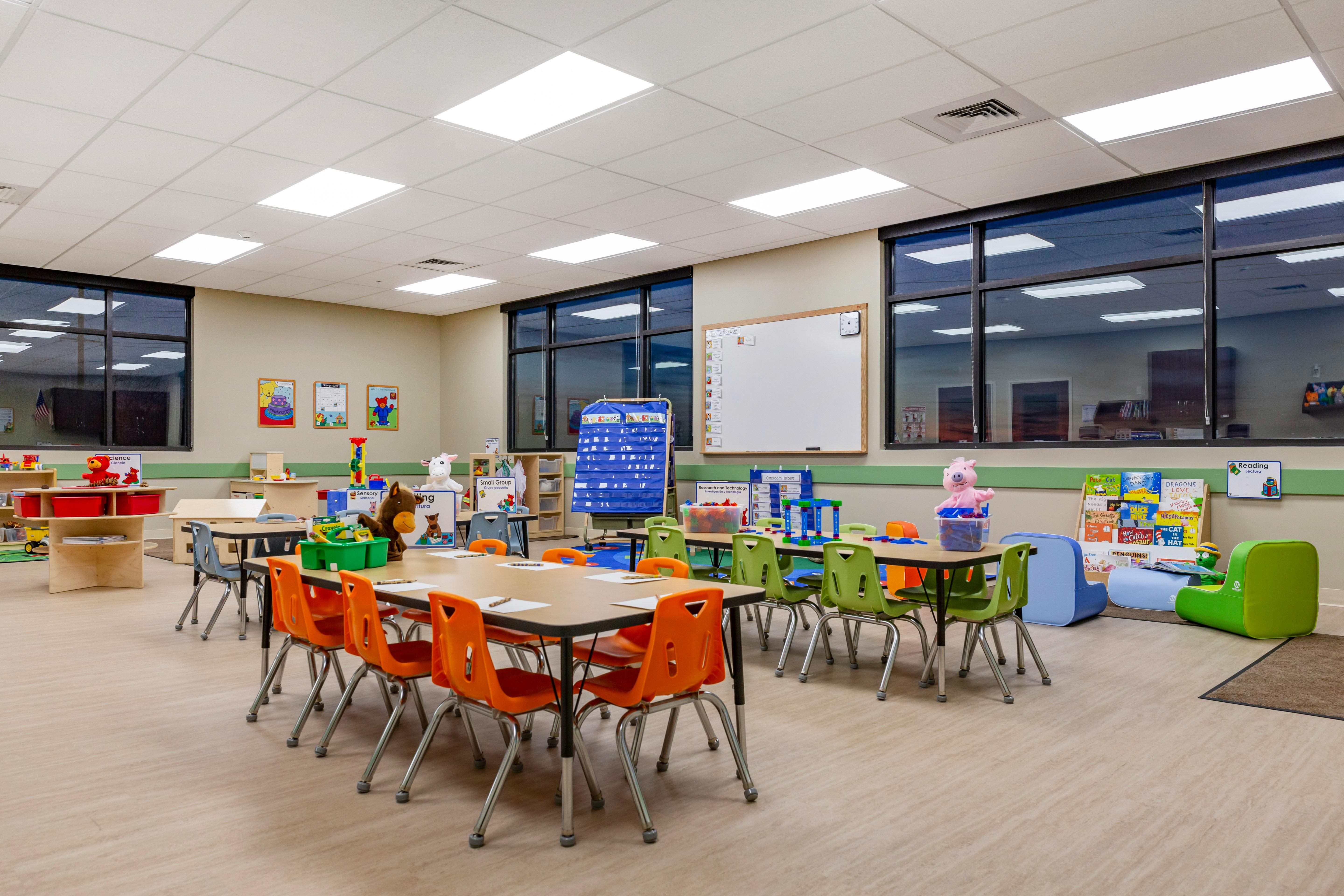 An empty classroom with tables, chairs, and learning materials