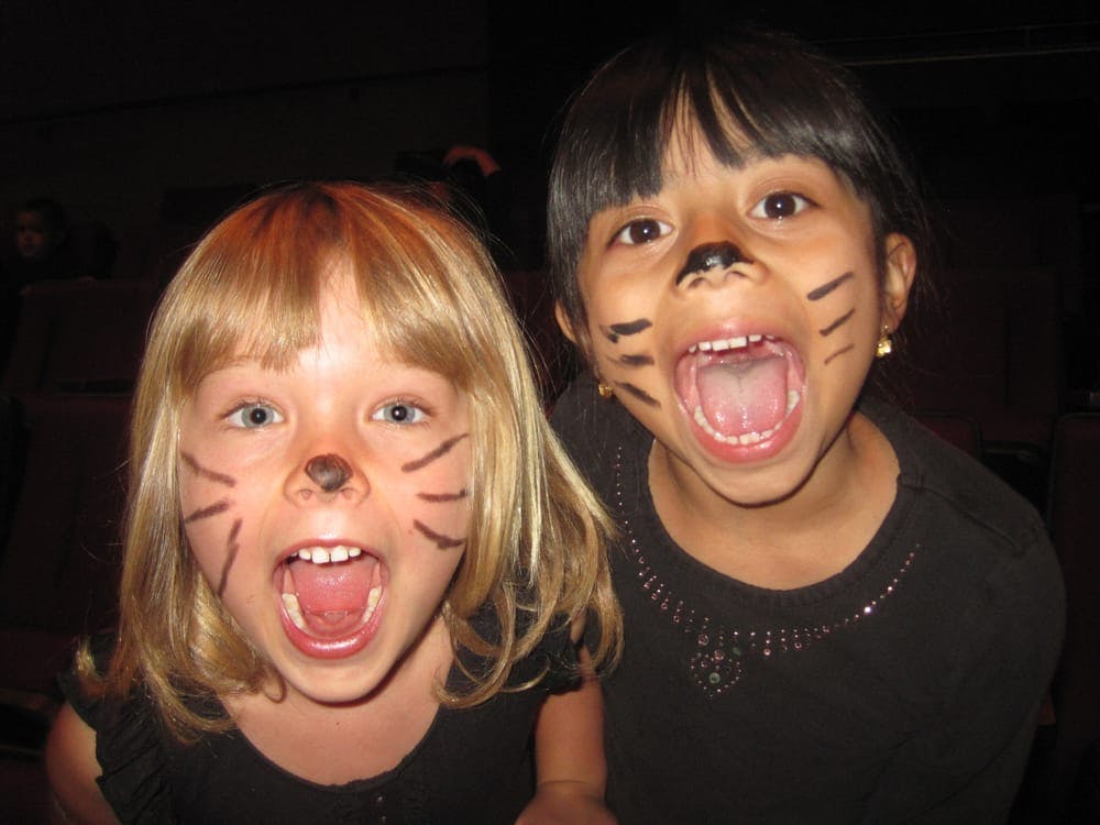Two children with painted cat faces yelling
