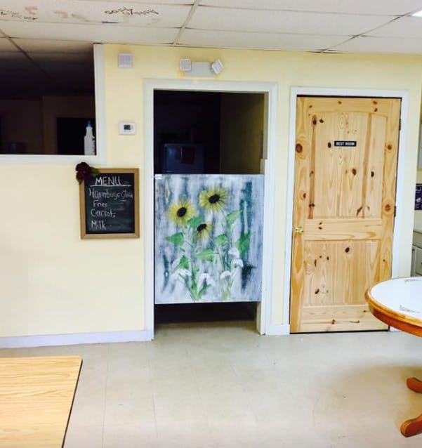 Chalkboard menu next to a doorway with a sunflower painting