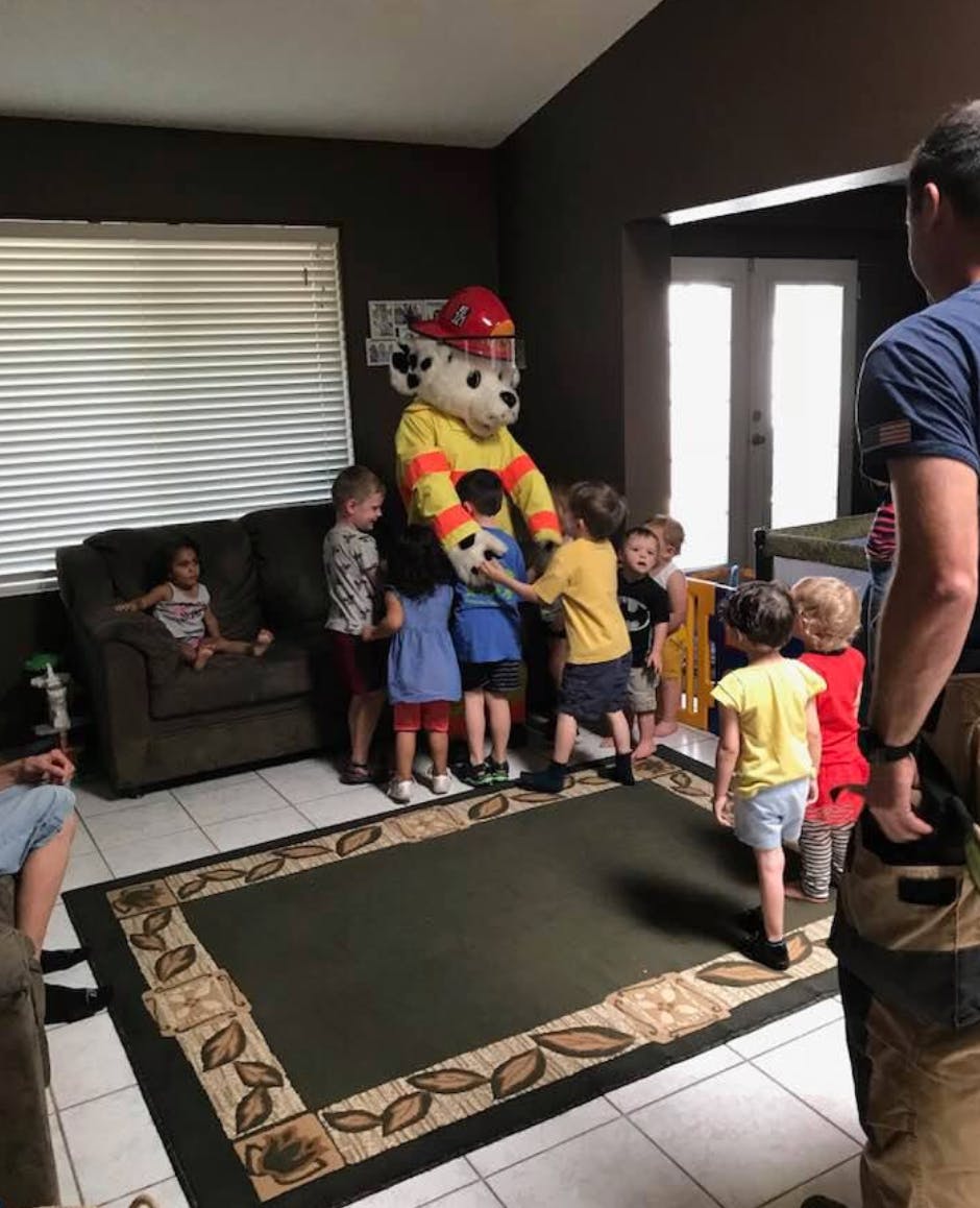 Mascot in firefighter costume surrounded by children