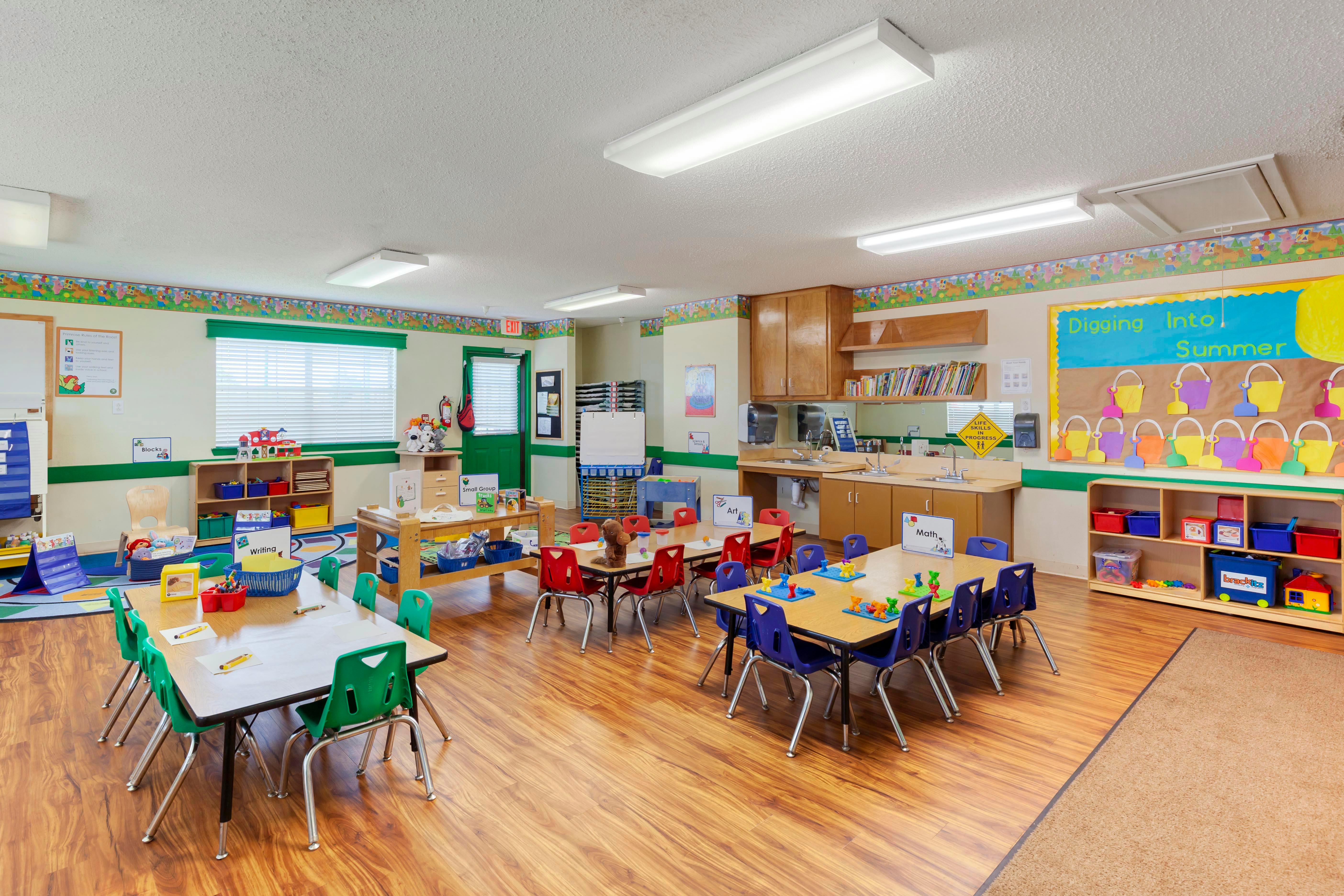 Classroom with child-sized tables and chairs, shelves with toys, and classroom decorations