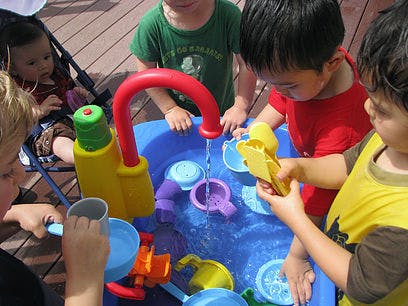 Children playing with a water table and toys
