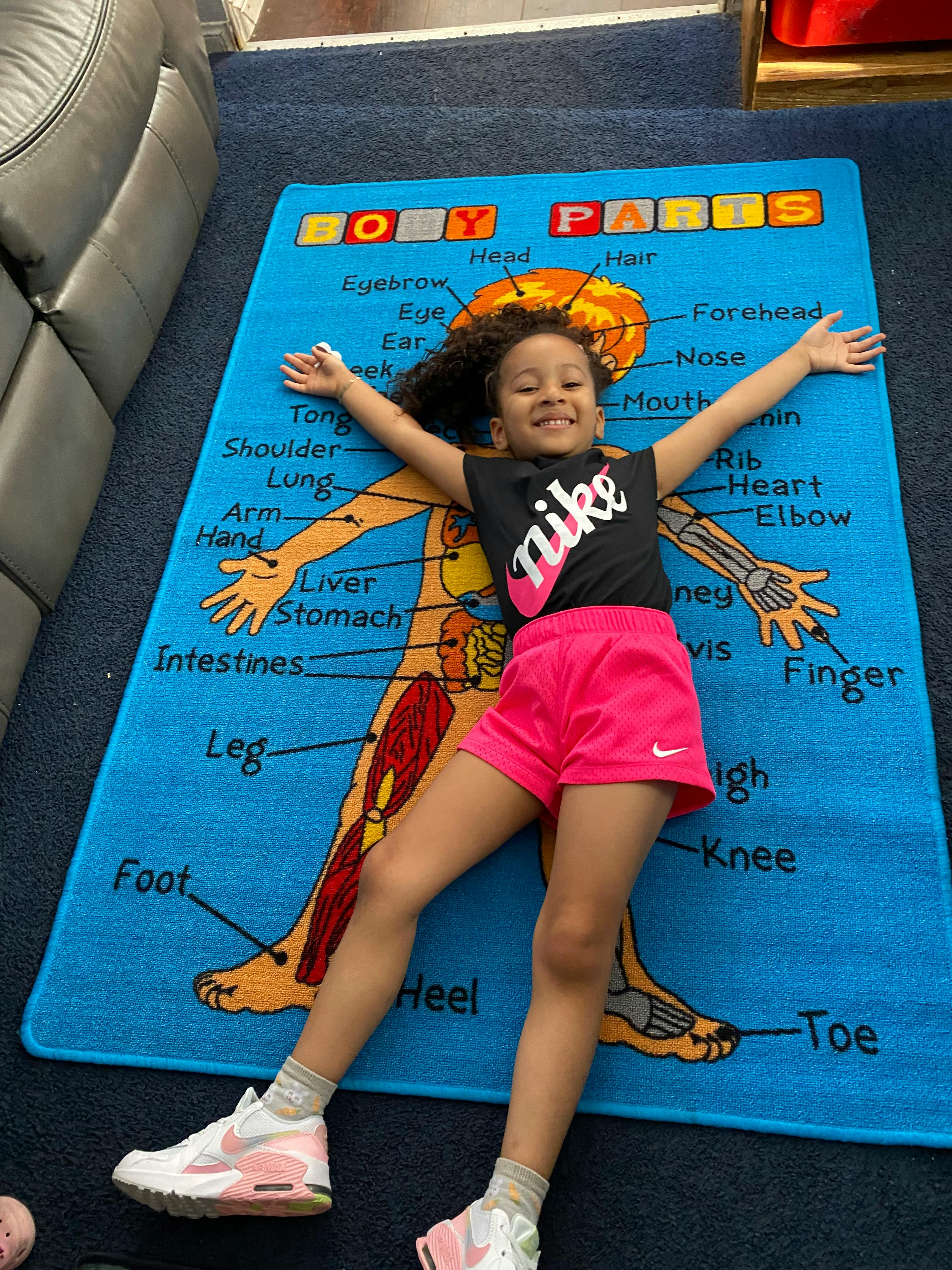 Child lying on a rug labeled Body Parts
