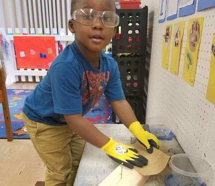 Child in safety glasses and gloves sanding wood