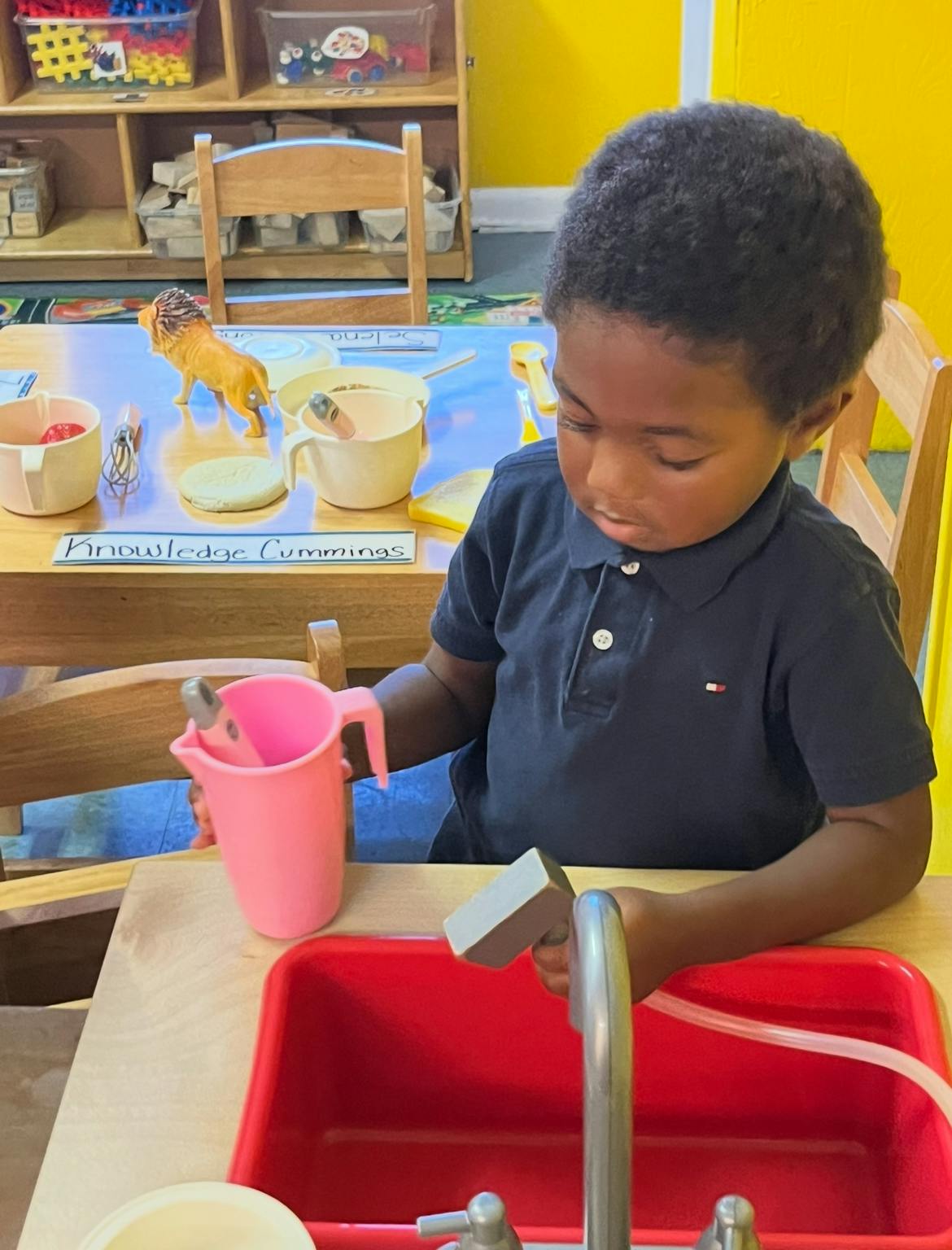Child playing with a toy sink and pitcher