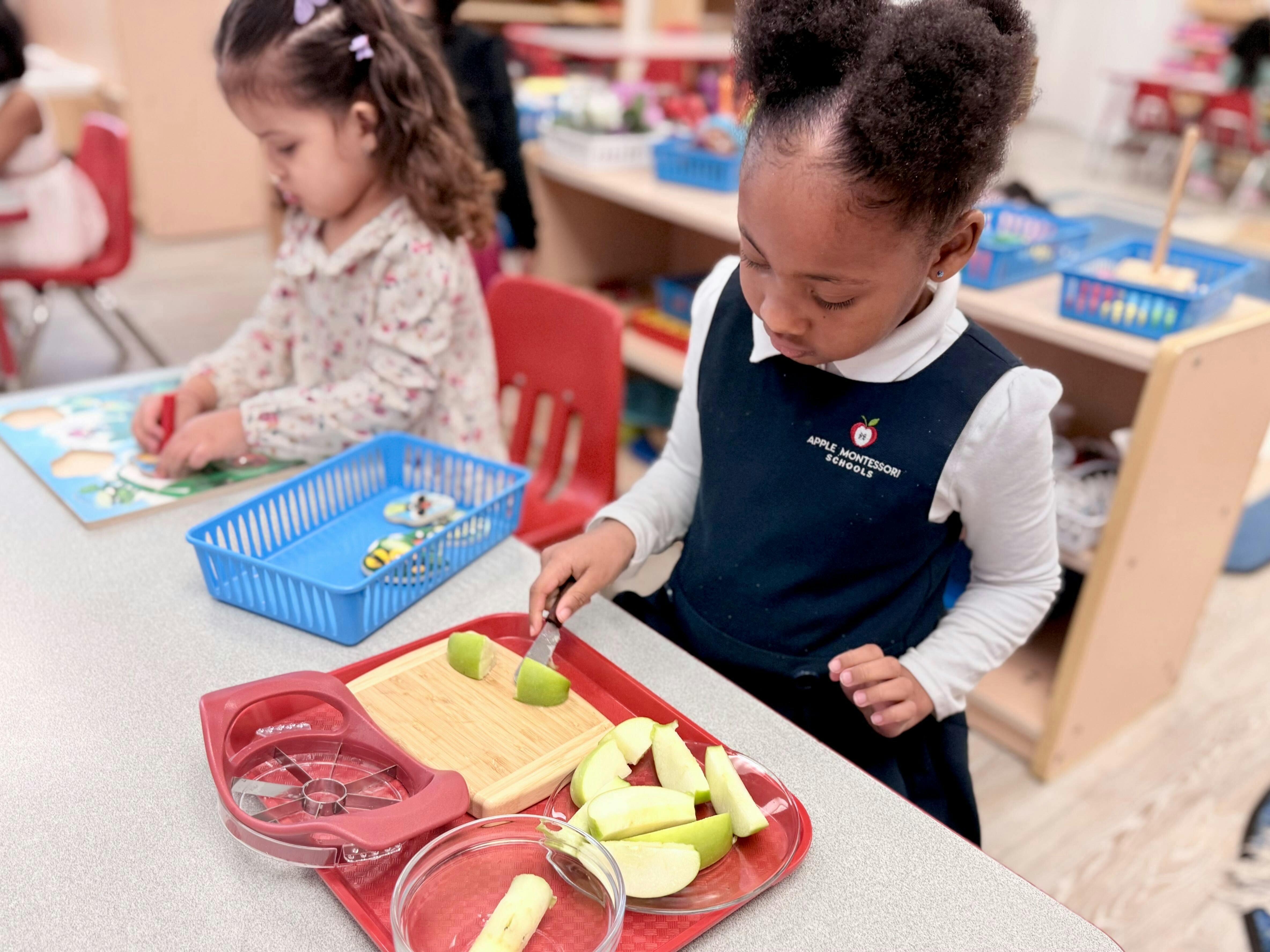 Child slicing green apples on a cutting board, another child in background