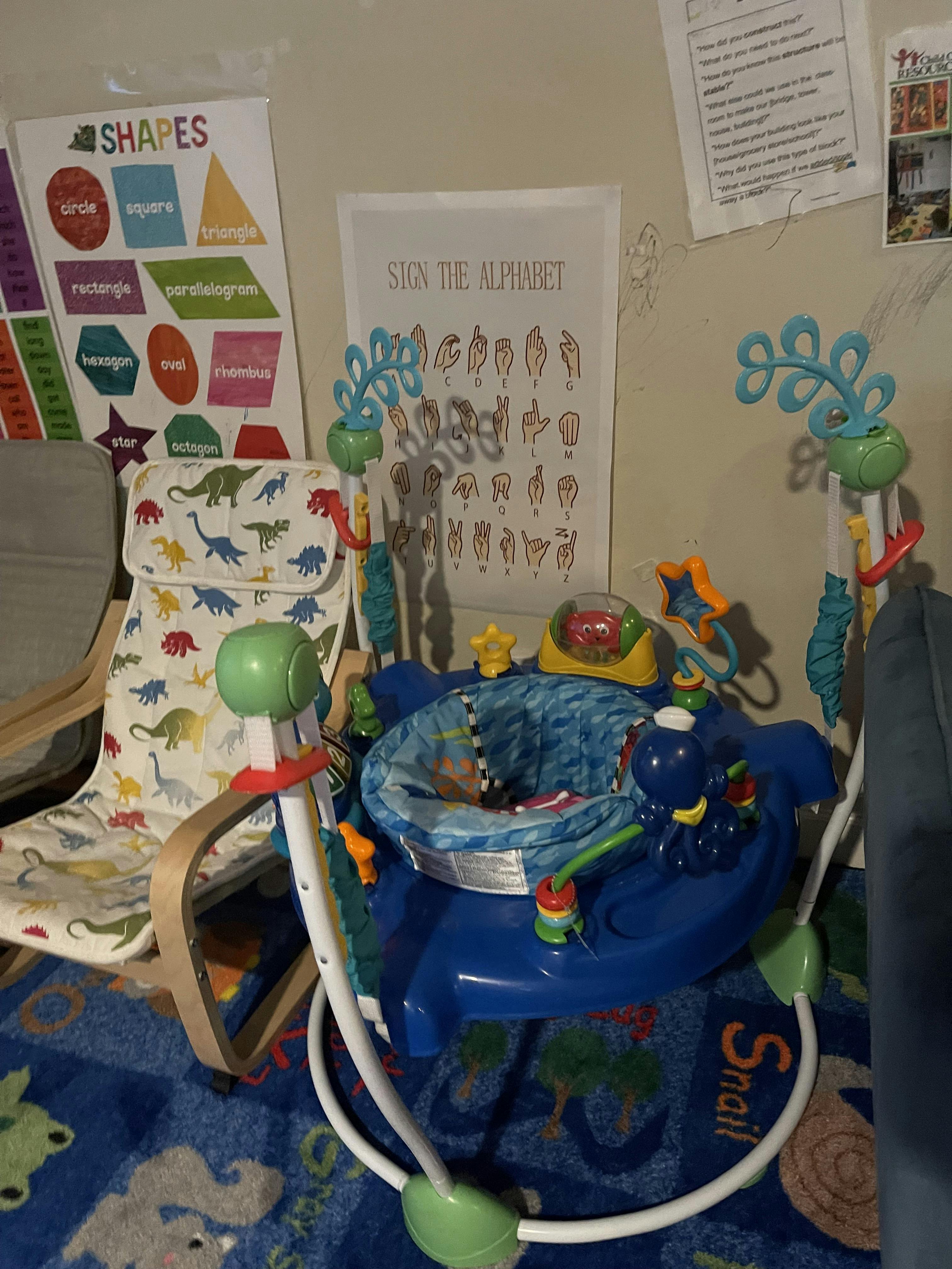 Baby activity jumper with attached toys in a play area
