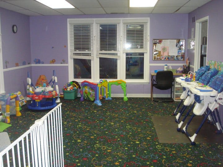 Playroom with various baby toys, high chairs, and a desk
