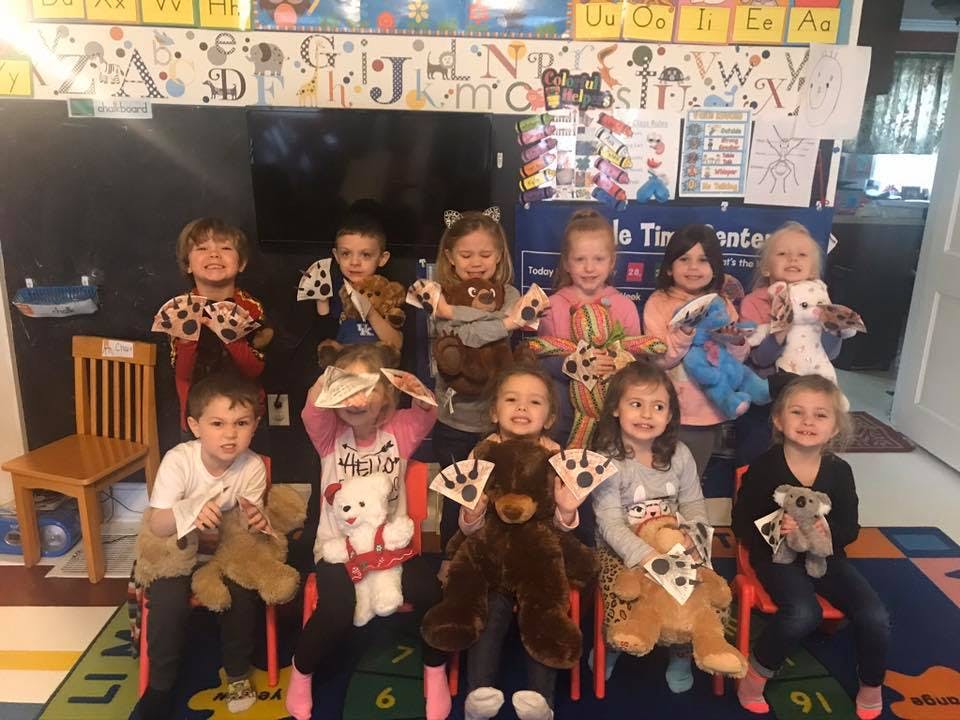 Group of children holding stuffed animals in a classroom