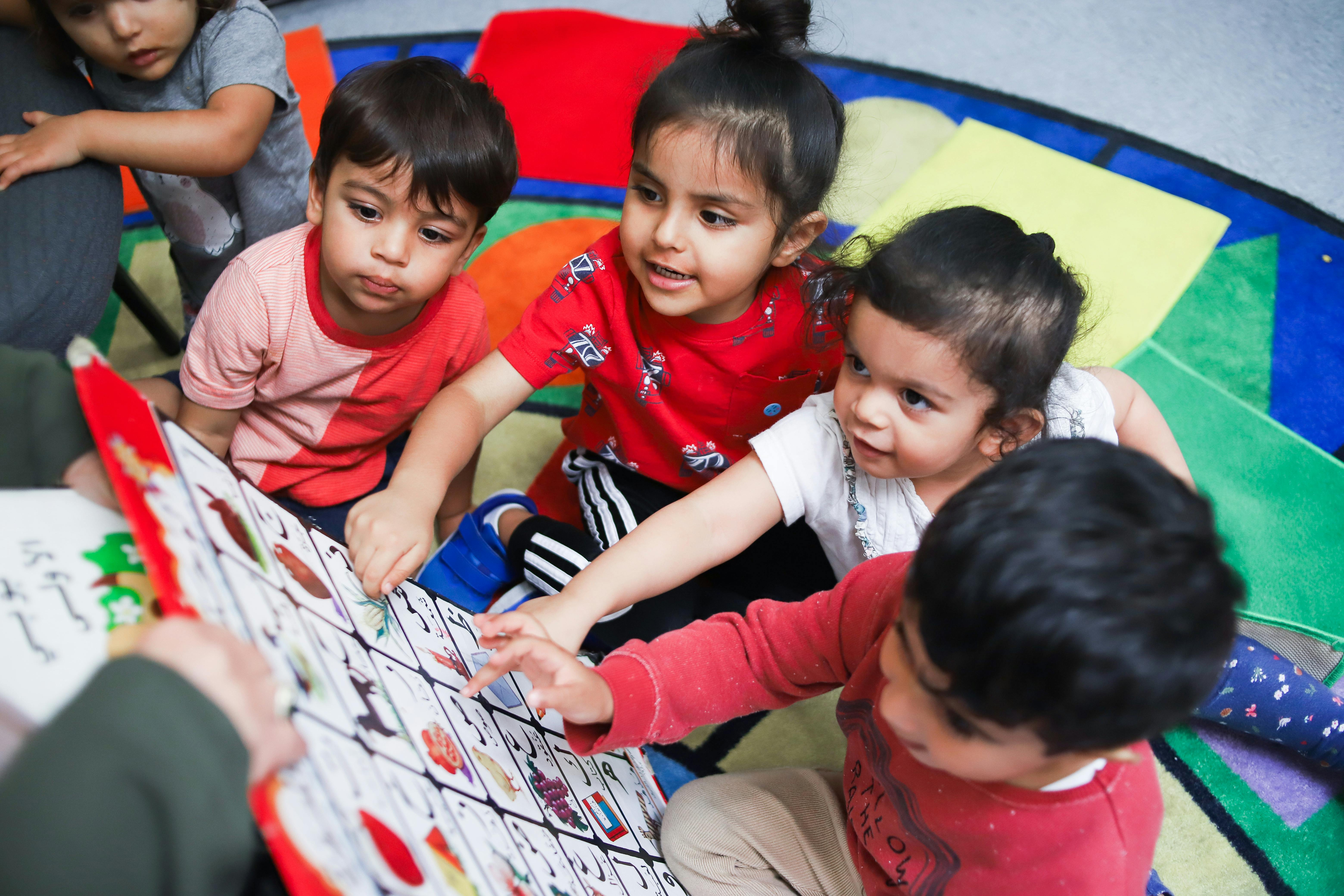 Children sitting on a rug looking at a large book