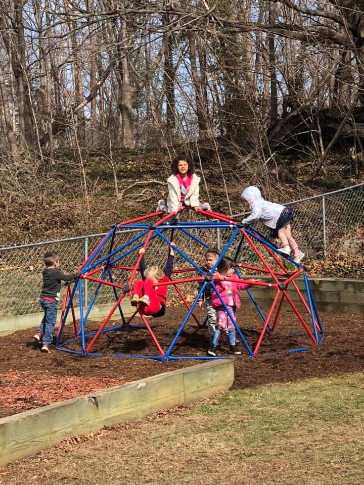 Adult and children playing on a red and blue geodesic dome climber