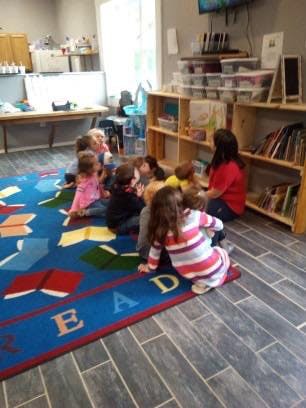 Adult and children sitting on a rug in a classroom