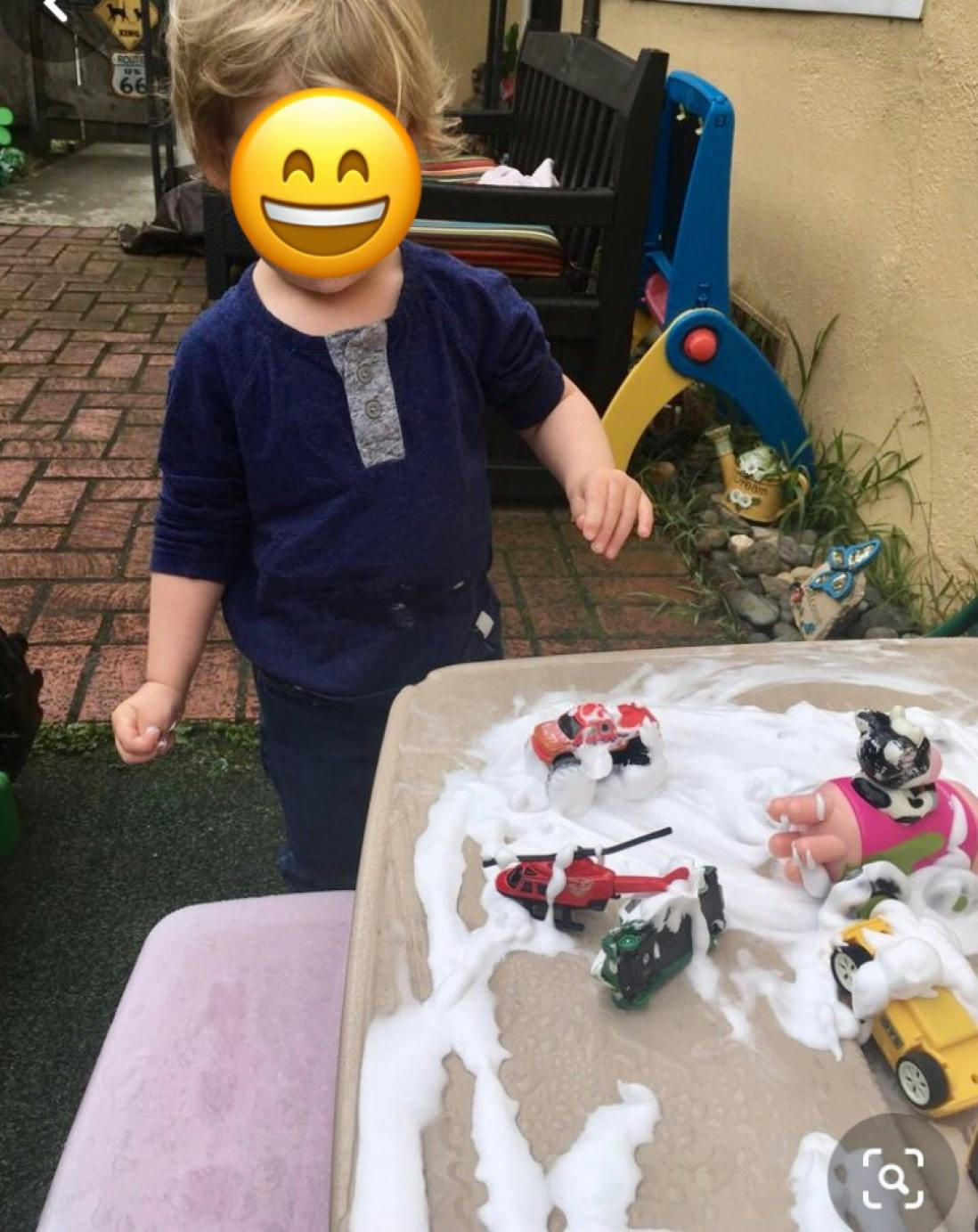 Child standing next to a table with toys covered in foam