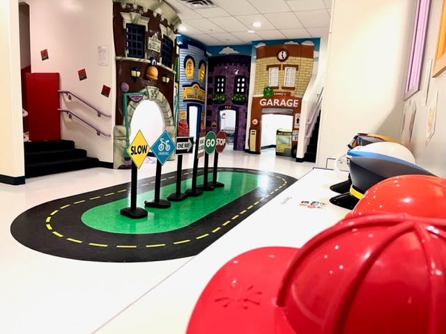 Indoor play area with a road track on the floor and miniature buildings