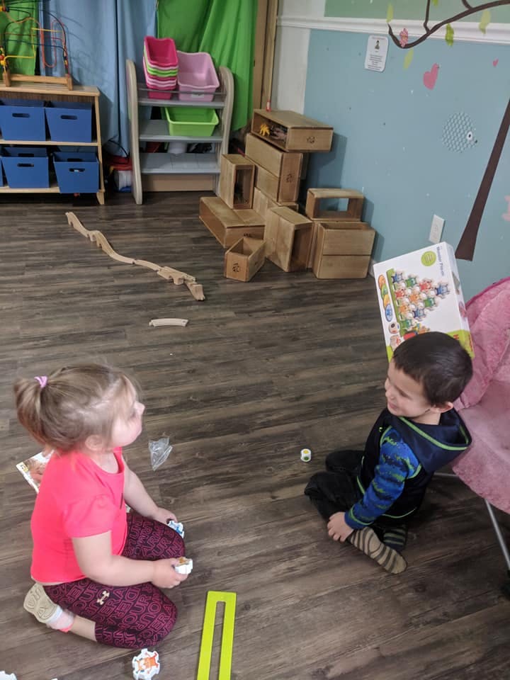 Two children sitting on the floor playing with toys