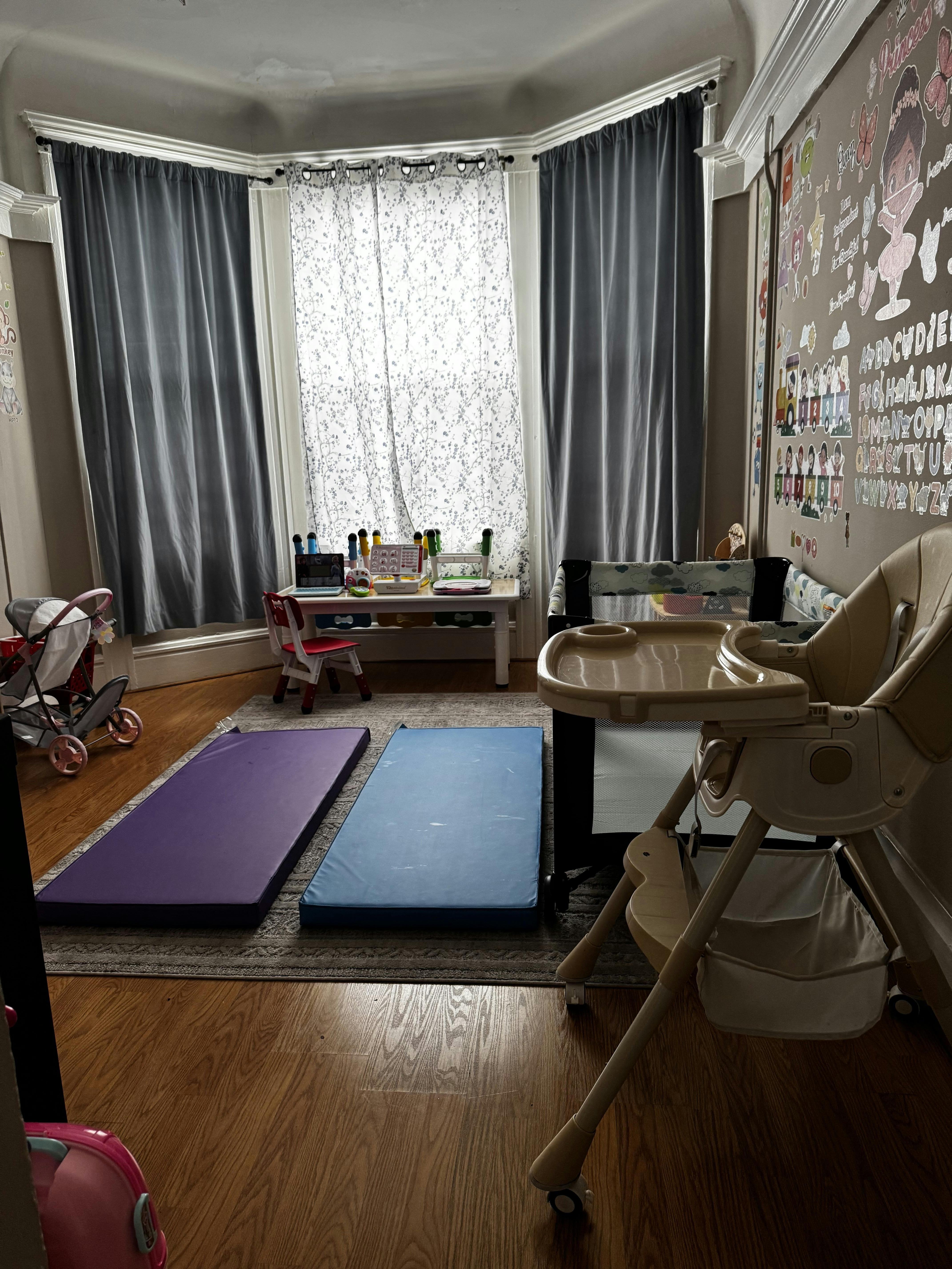 Baby room with a high chair, playpen, small table with chair, and two mats