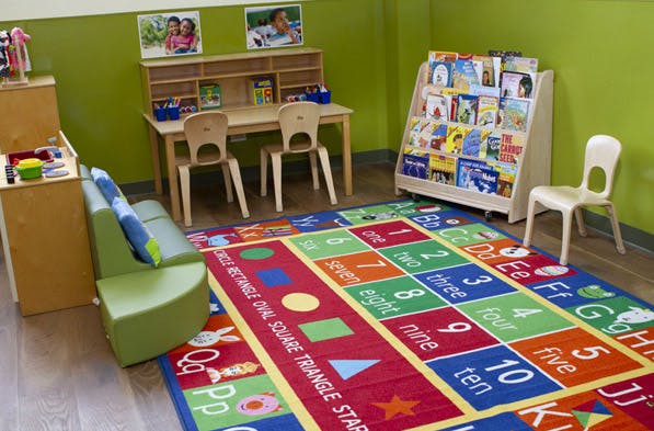 Classroom with colorful rug, small table and chairs, and book display