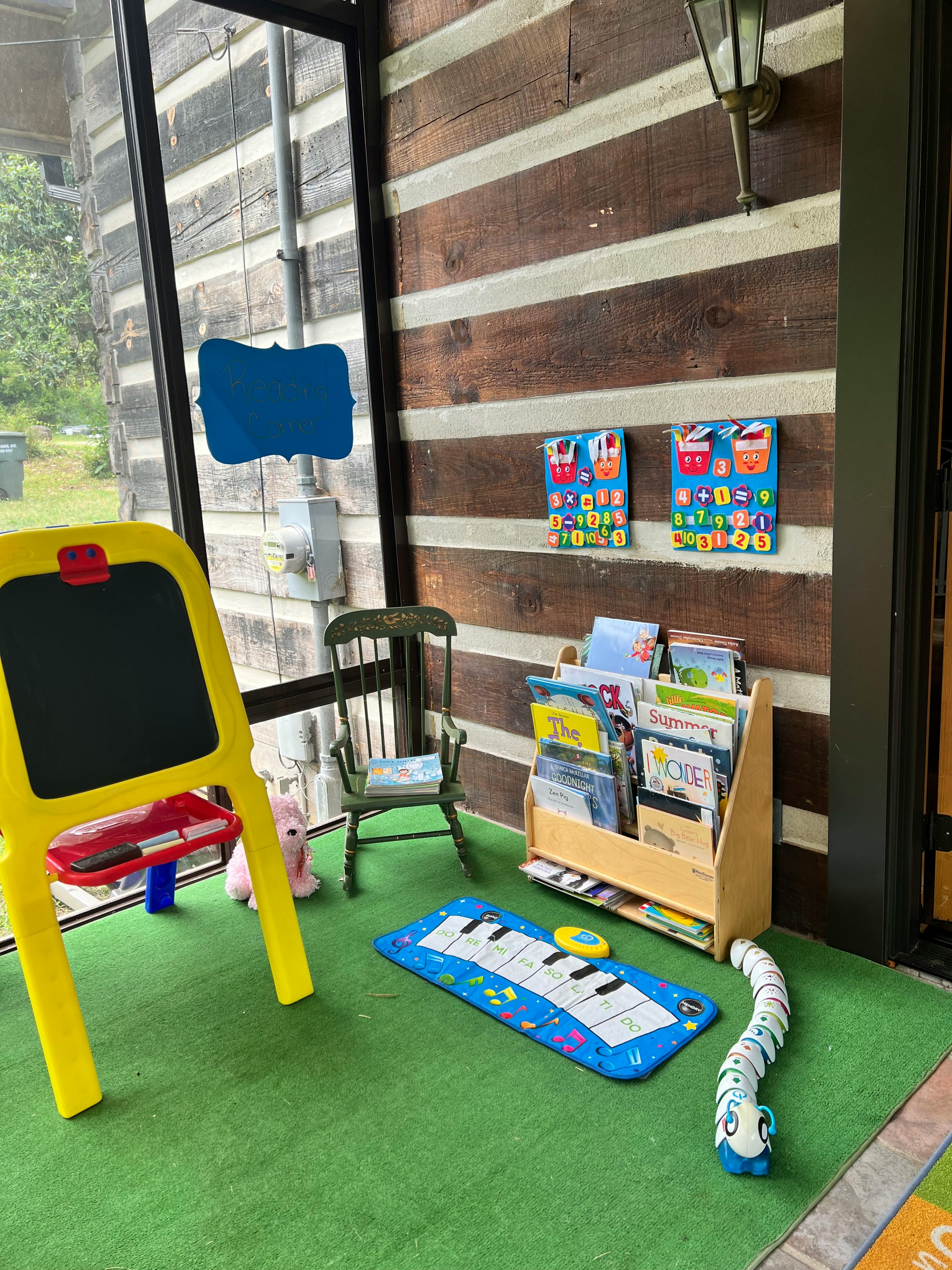 Children's play area with easel, chair, bookshelf, and piano mat