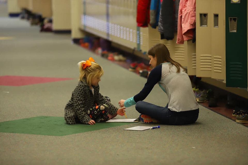 Person and child sitting on floor in hallway, looking at papers