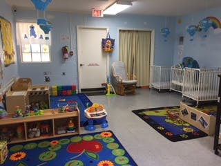 Childcare room with cribs, play mats, and toys