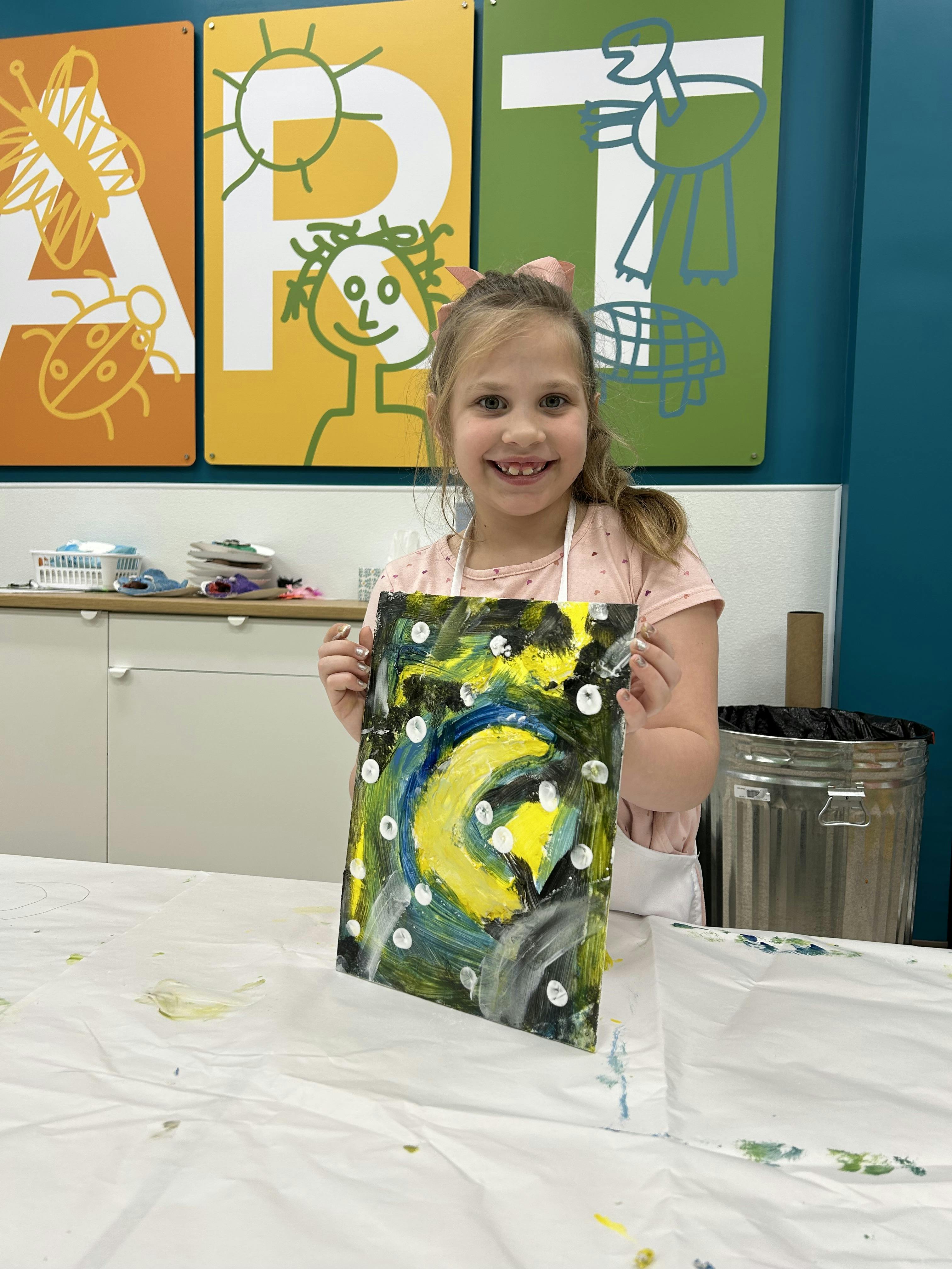 Child in an art class holding up their abstract painting