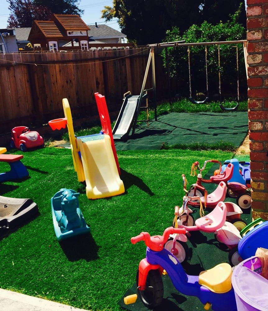 Playground with slides, swings, and tricycles on artificial turf