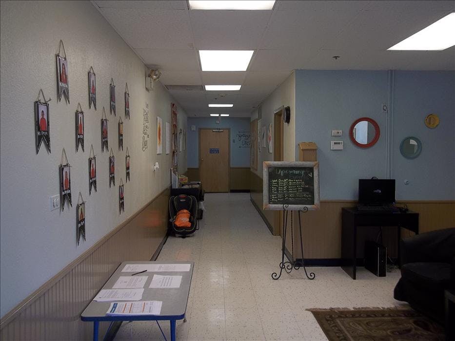 Hallway with a bulletin board, a table with papers, and a chalkboard sign
