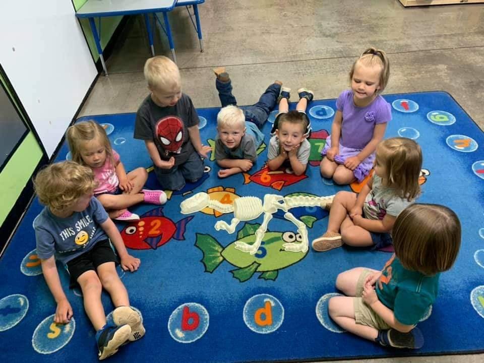 Children sitting on a blue rug with fish designs