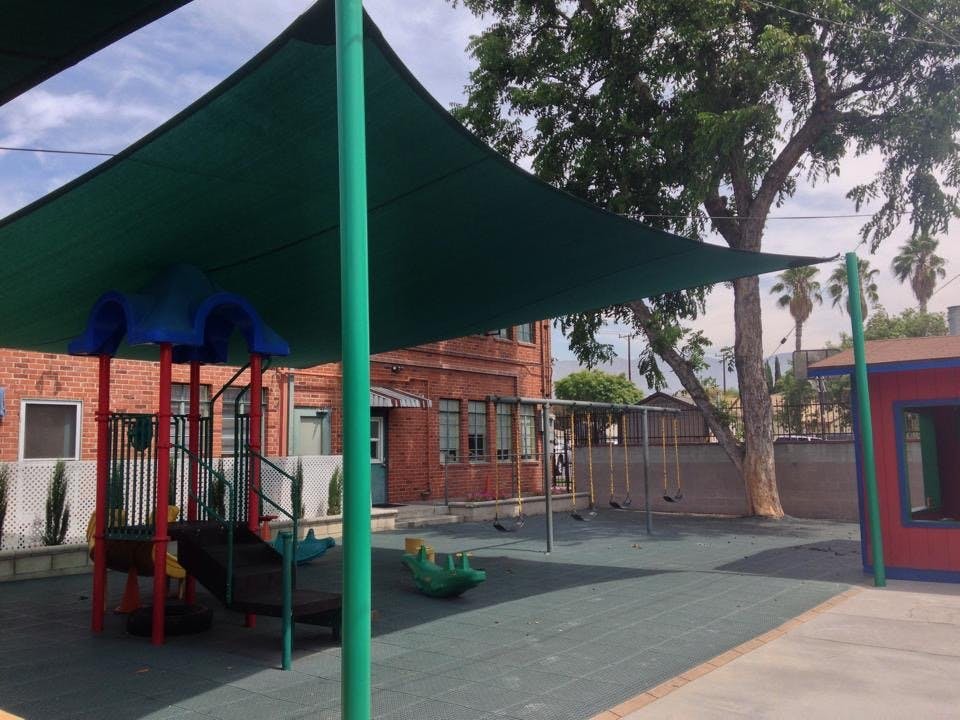 Playground with shade structure, play equipment, and brick building