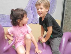 Two children playing on a purple toy