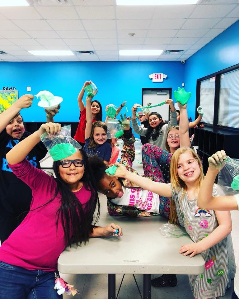 Group of children holding up bags of slime in a classroom
