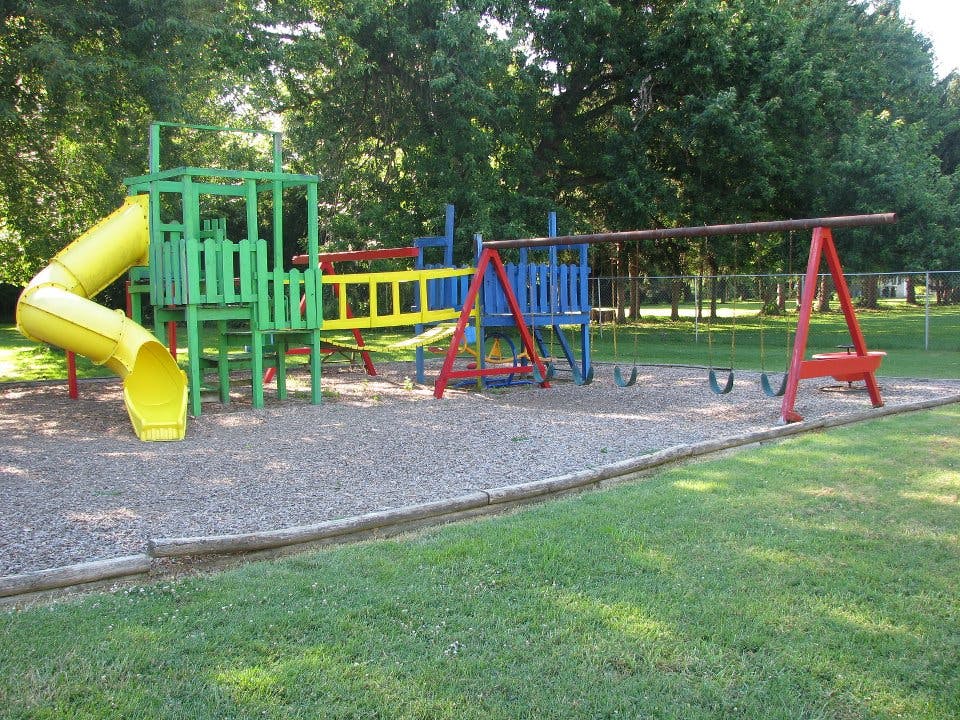 Playground with a yellow slide, green climbing structure, and swings
