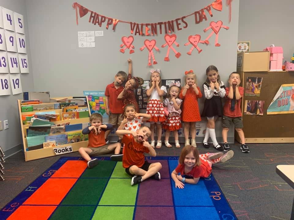 Group of children posing in a classroom with Valentine's Day decorations