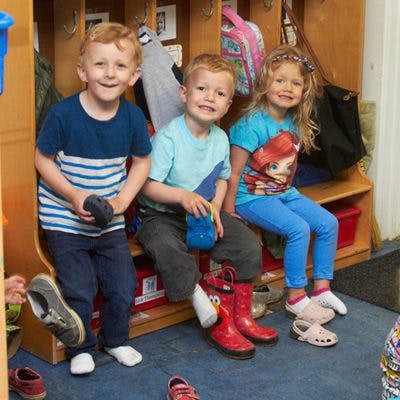Three children sitting on a bench in a classroom