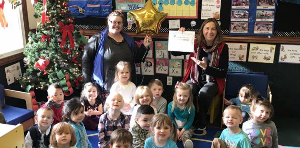 Two people with a group of children in a classroom