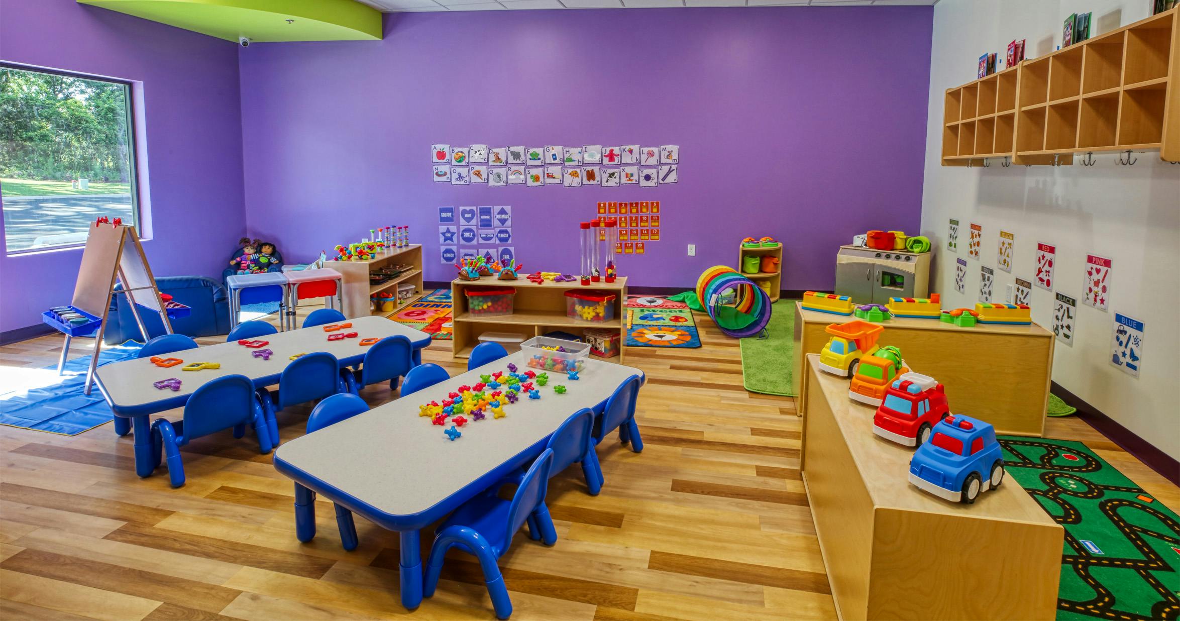 Colorful playroom with small tables and chairs, alphabet charts, and toys