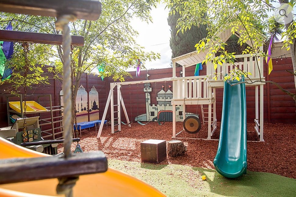 Outdoor playground with a white playset, blue slide, and swing set