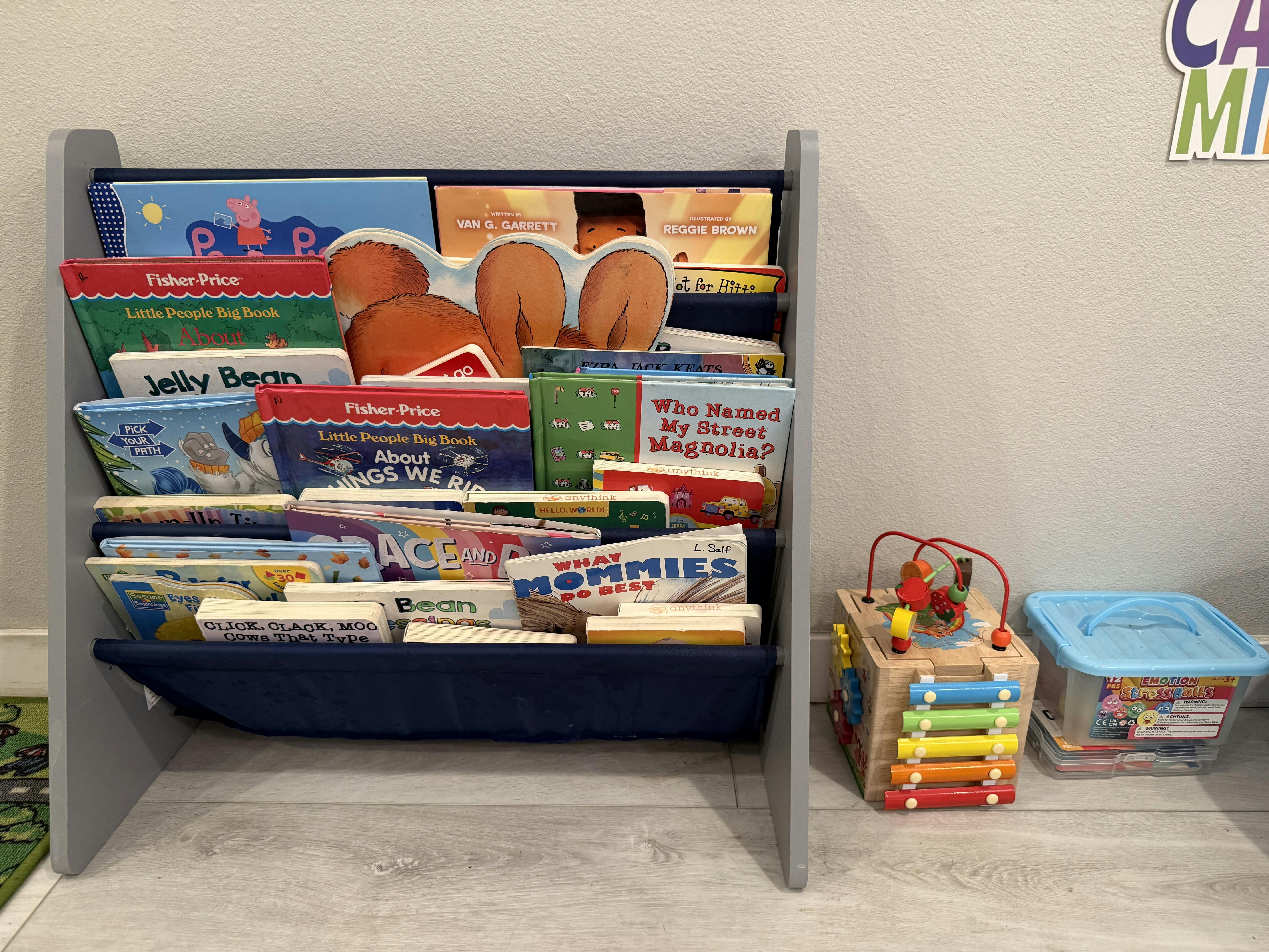 Children's book rack filled with various books next to a wooden activity toy