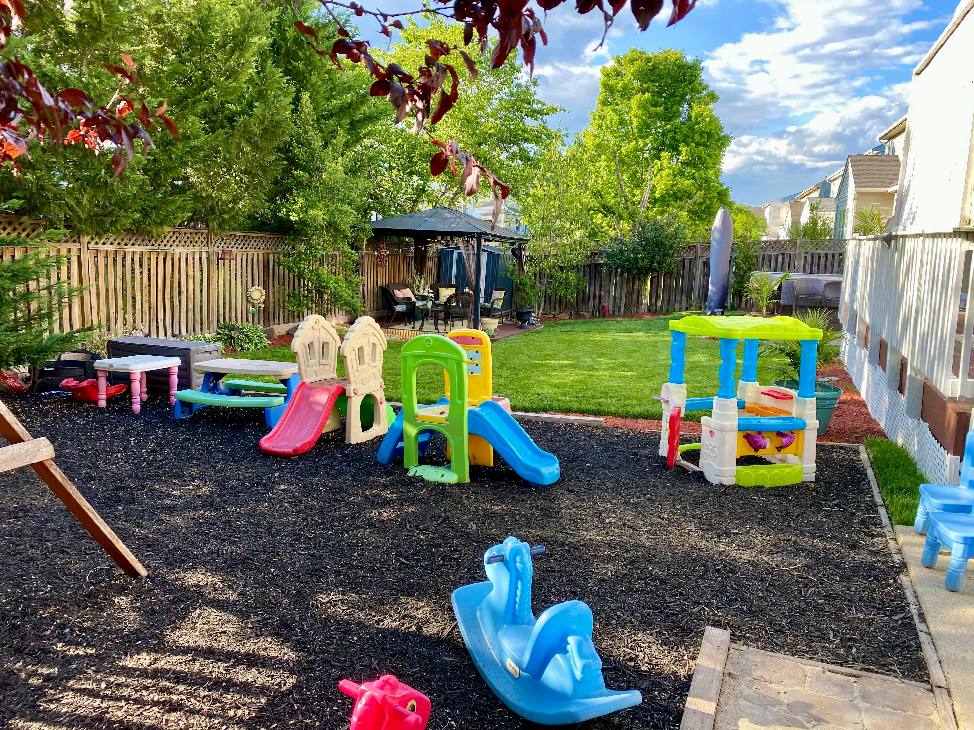 Outdoor playground with colorful slides and play structures on dark ground cover