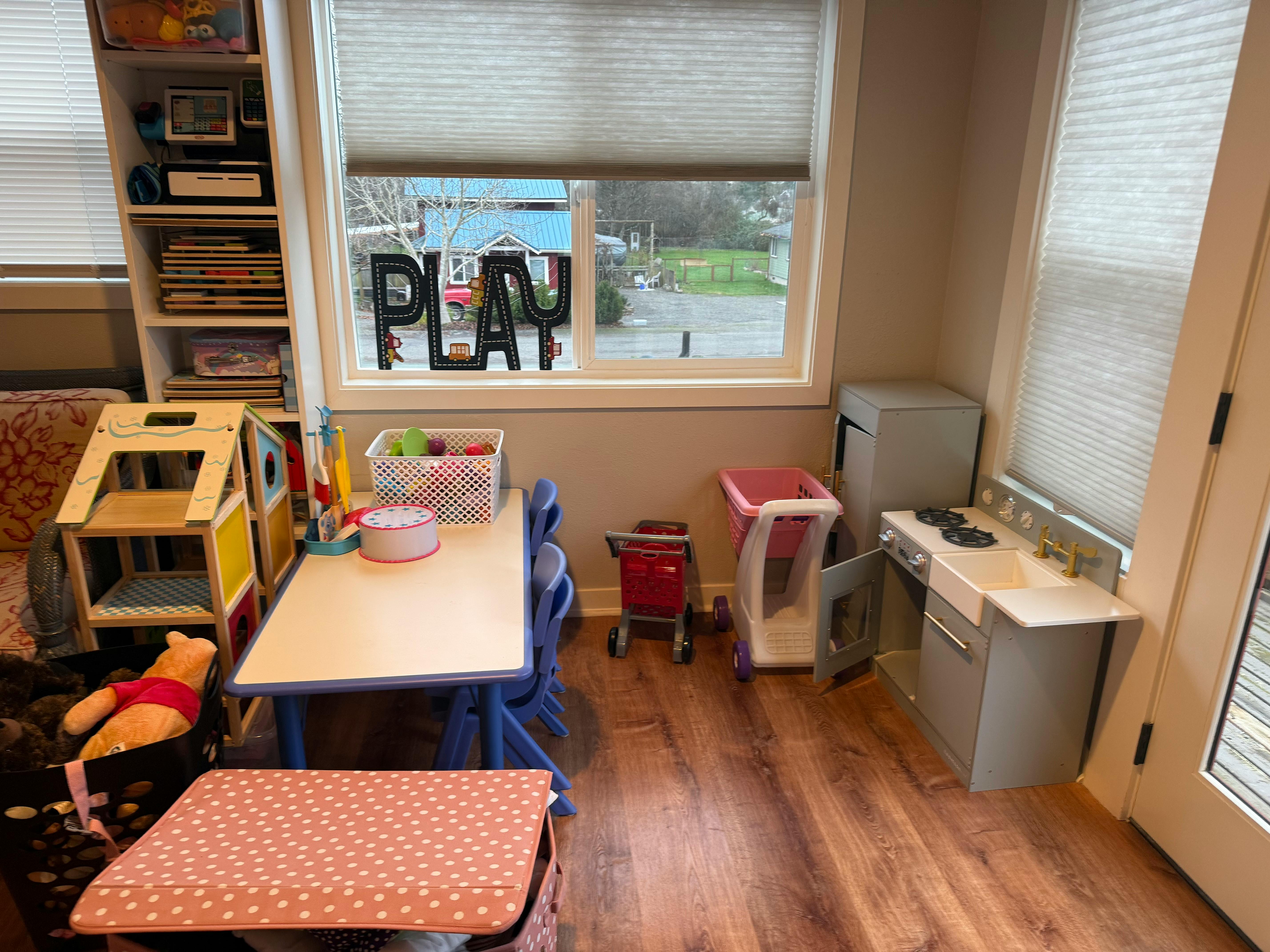 Children's play area with toy kitchen, table, and dollhouse