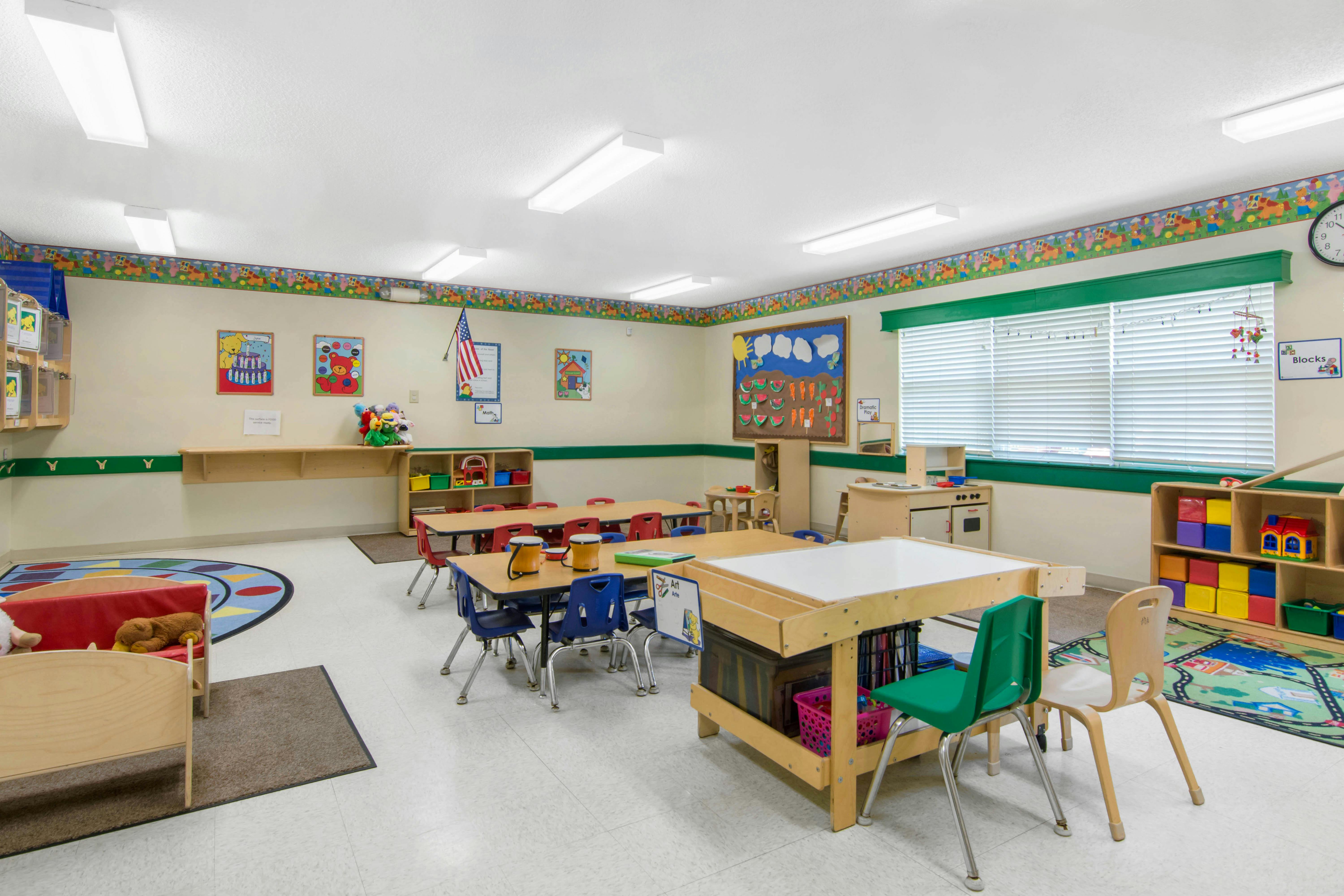 Classroom with small tables, chairs, and play areas