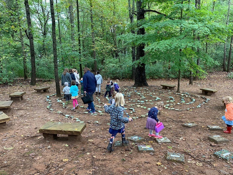People and children walking on a winding path in a wooded area