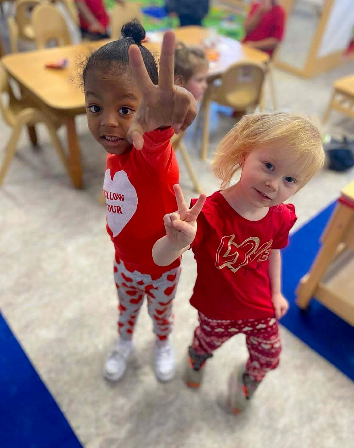 Two children in red shirts making peace signs